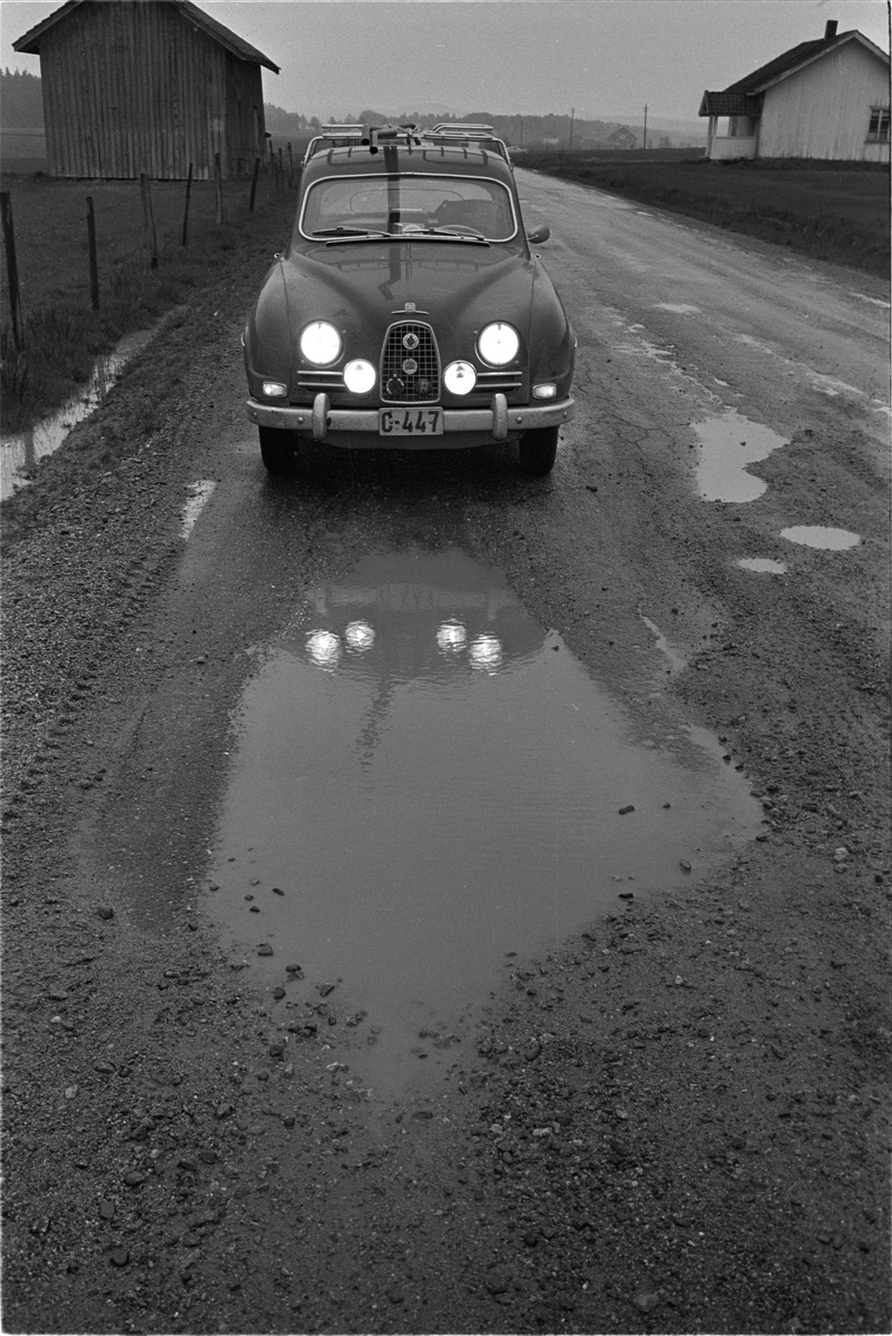 Riksvei 1 fra Svinesund fotografert i mai 1963. Bilen har fronten nordover på Rv1 som gikk igjennom gården Øvre Hjelmungen ved Halden.
Veien ble lagt utenom gården 1981.
