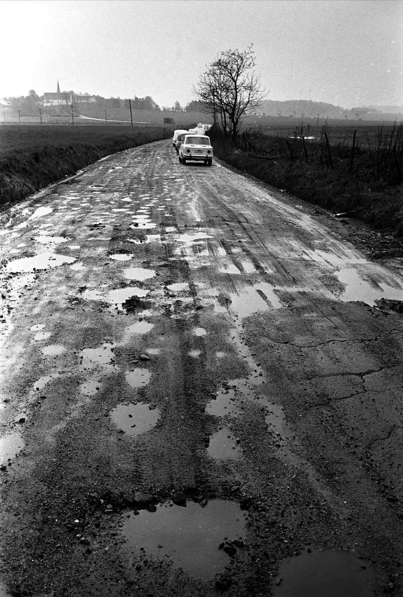 Riksvei 1 fra Svinesund, mai 1963. Landskap med sølete vei og biler.