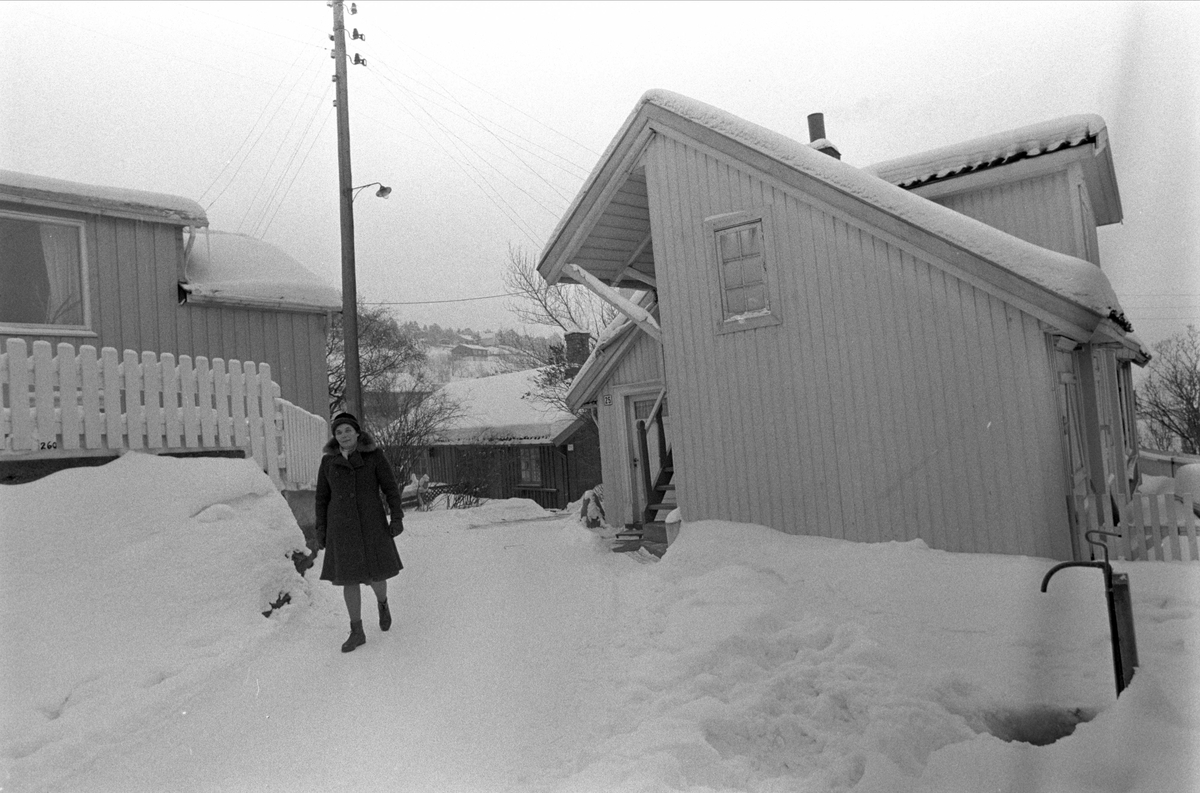 Drøbak, Frogn, 01.03.1970. Kvinne i bygate med snø. Trehusbebyggelse.