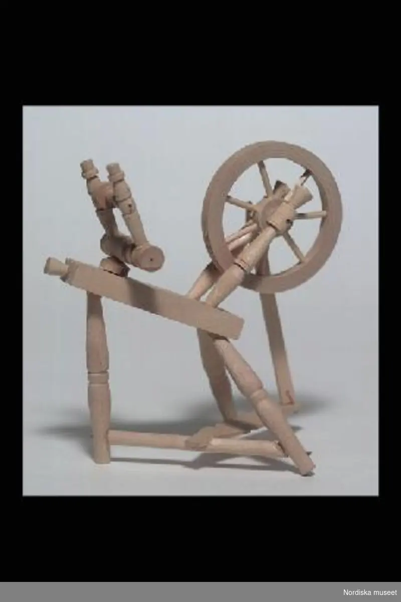Inventering Sesam 1996-1999:
L 14   B 13  (cm)
Spinnrock, leksak, av obehandlad björk, tre ben, spinnhjul och trampa, spole. 
Undertill märkt med gummistämpel "Ros¿ns Eftr.".
Tillverkad av givaren 1952.
Birgitta Martinius 1997