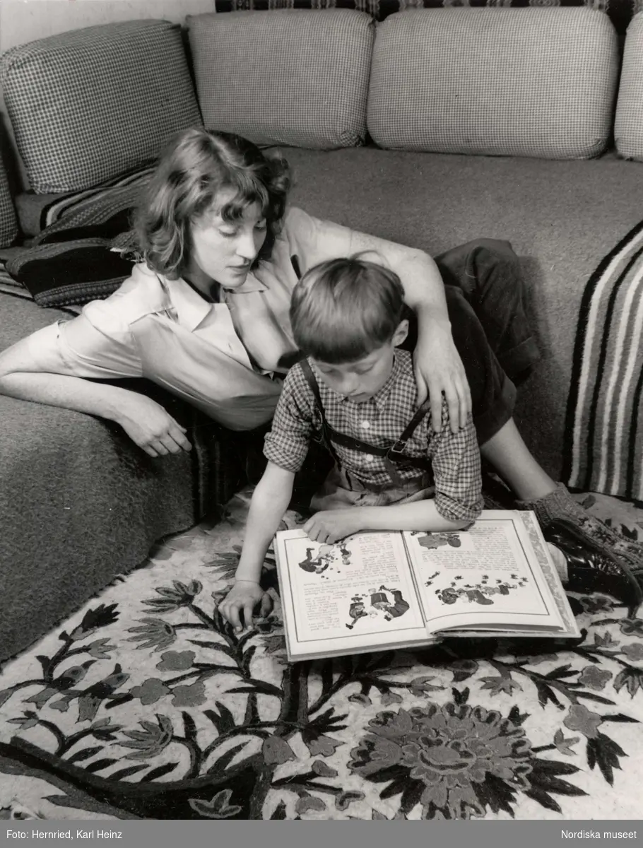 Kvinna och pojke sitter på golvet och läser sagobok