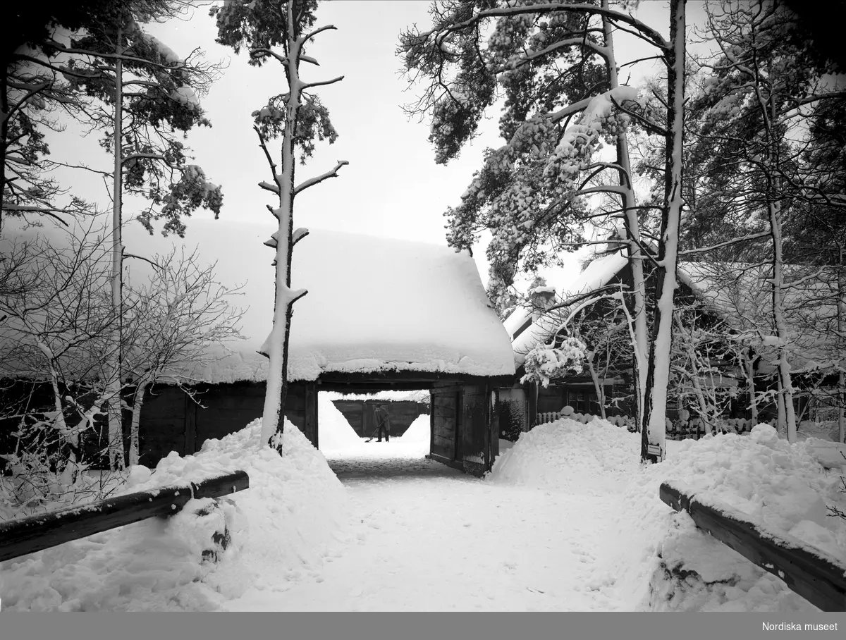 Oktorpsgården på Skansen. En man skottar snö inne på gården.