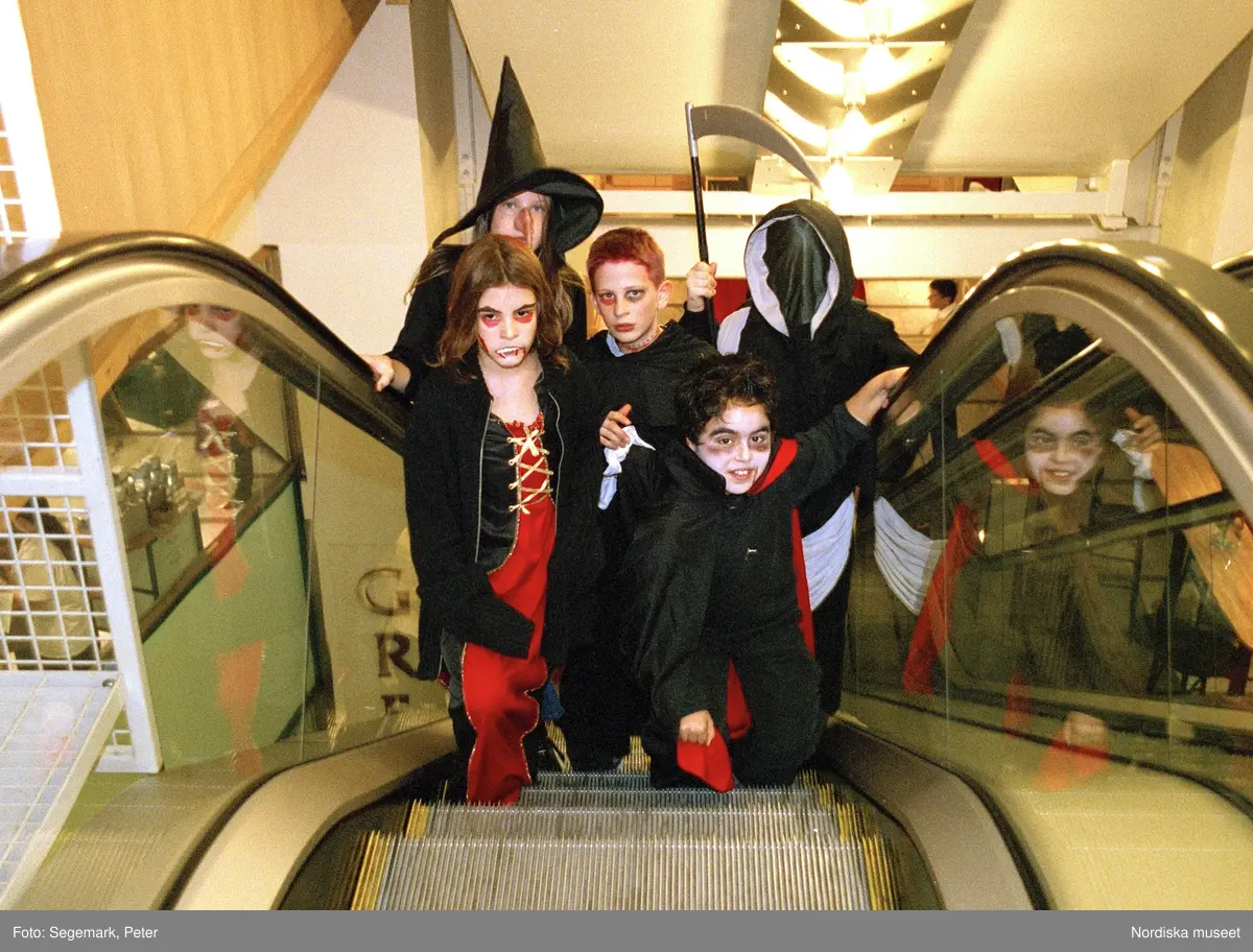 Utklädda barn i rulltrappa. Förberedelser och firande av Halloween ...