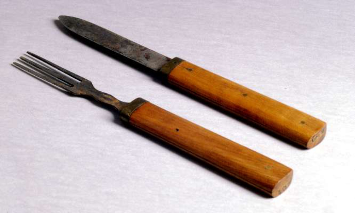 Kniv och gaffel av järn med träskaft, kan skjutas i varandra.



