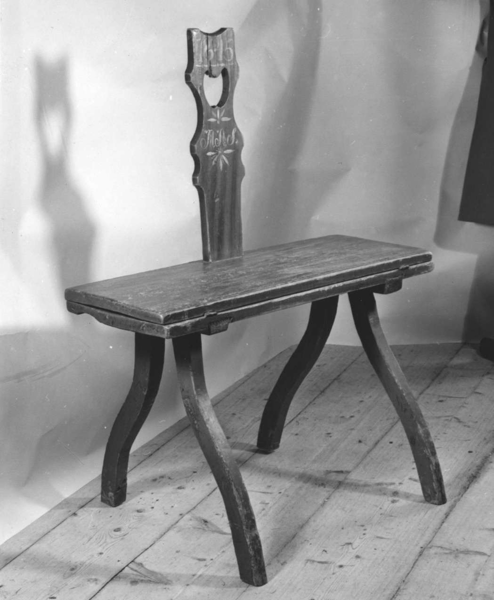 Bordstol av trä. Ryggstödet med handtag, märkt 1846 MAS med vit färg och de fyra svängda benen är intappade i var sin sitshalva. Sitshalvorna är förbundna med gångjärn. Mörkröd målning. Ryggstödets sidor blå.
