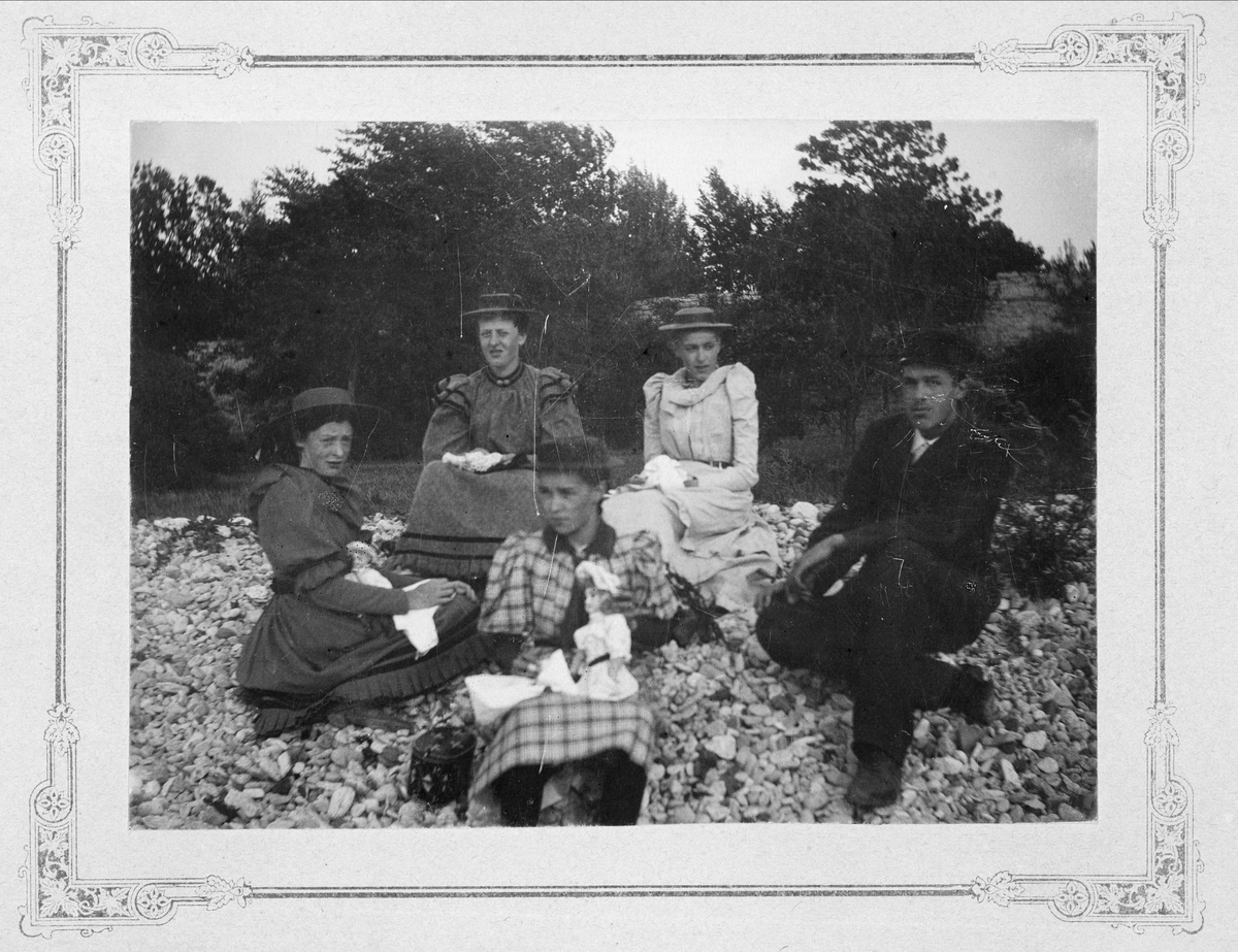 Grupporträtt - fyra kvinnor och en man på en stenstrand i Visby. Gertrud Nilsson sitter överst till vänster