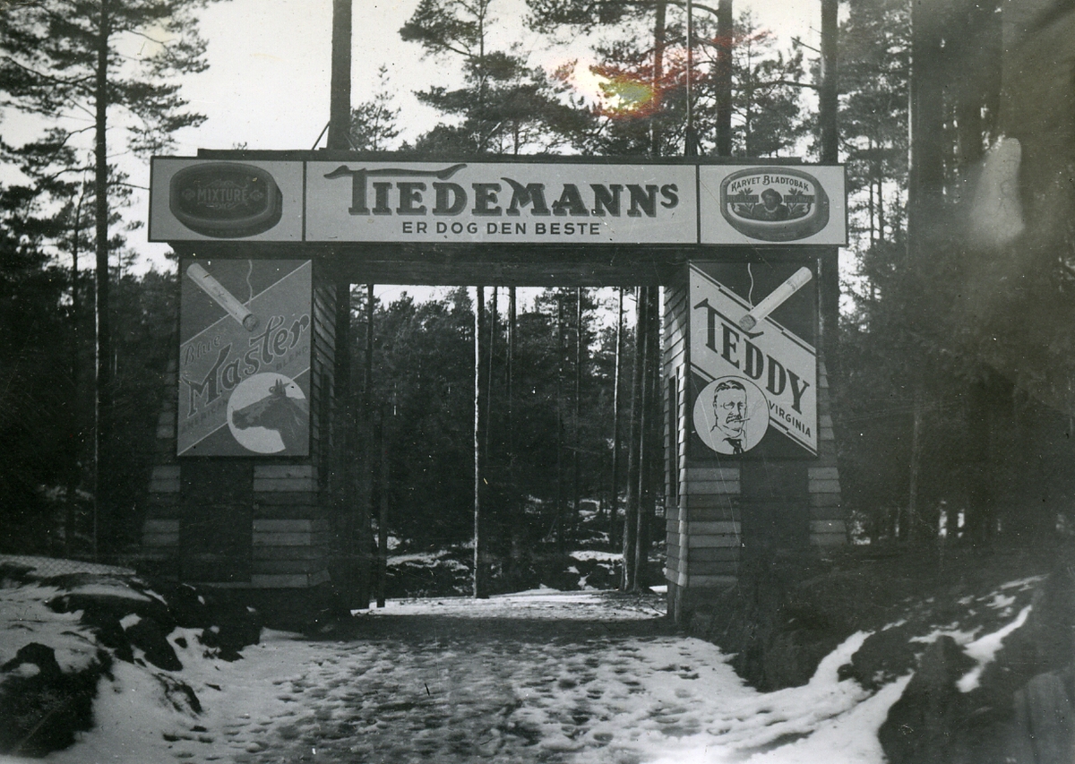 Inngangsportalen til idrettsplassen i Kragerø med reklame for Tiedemanns Teddy og Blue Master sigaretter.