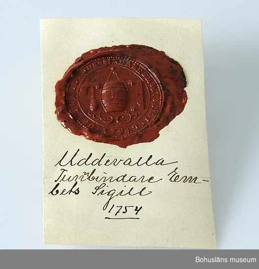 Föremålet visas i basutställningen Uddevalla genom tiderna, Bohusläns museum, Uddevalla.

Uddevalla tunnbindareämbetes sigill 1754 i rött sigillack, uppklistrat på en vit kartongbit med handskrivna texten:
Uddevalla 
Tunnbindare
Em-
bets Sigill 
1754

På sigillet avbildat en tunna, ett bandjärn och en däxel.
Sigillet är 4 cm diam.

Tillverkningstid avser sigillstampen som bör vara gjord då eller möjligen senare. Själva sigillet kan vara tillverkat senare.