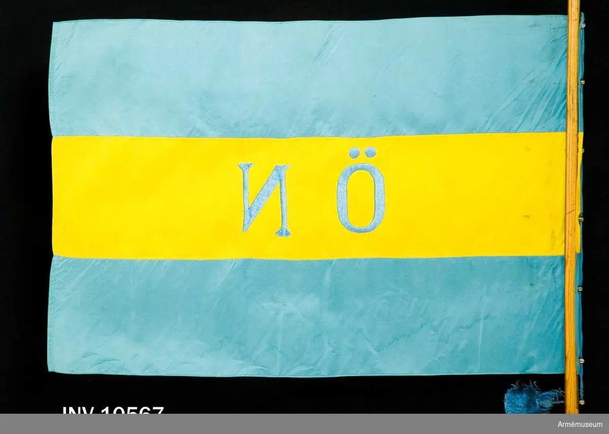 Grupp B I.

Blå och gul flagga sydd i tre våder, varav den i mitten är gul.  Sidenflagga. Mitt på det gula mittsidenet är broderat med blått  silke "ÖN". Fastsatt med silkesnodd som dragits genom kulor med hål. Inl enligt go 19510928 nr 3596.

Samhörande stång?, fodral, skyddsduk. 
