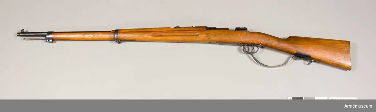 Grupp E II f.
Modellexemplar med extra "varbygel"  Gevärets tillverkningsnummer: 11003. Samhörande gevärsrem, vid geväret fästad fastställningslapp på vilken skriften delvis är oläslig.