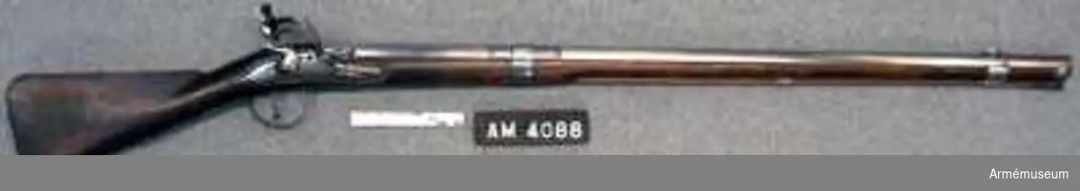 Karbin med flintlås.
Nominalkaliber 19 mm, verklig kaliber 19,1 mm. Kulvikt 32,25 g. Loppets rel. längd: 860 mm. Karbinen överensstämmer fullkomligt med AM 1932:4087. På kammarstyckets översida finns en kronstämpel och en stämpel med bokstaven S. På vänstra sidan sitter en otydlig stämpel och på undersidan en stämpel med D H, en troligen med H och dessutom är ett andreaskors inhugget där. På låsbleckets utsida sitter en stämpel med ett monogram av bokstäverna I N R.

På kolvens högra sida sitter en fastklistrad pappersbit på vilken står "1704 års carbin". På samma sida är siffran 2 och numret 112 inslagna. På kolvens vänstra sida finns spår av ett rött lacksigill. På kolvändens av bakplåten obeteckta del är en stämpel med bokstäverna N T i monogram (väl Norrtälje) inslagen två gånger och dessutom finns där en annan stämpel med bokstäverna M S. Laddstocken är av trä och har i tjockänden skoning av horn. På smaländen sitter ett 12,3 cm långt järnbeslag, som är försett med ett 12,3 cm långt järnbeslag, som är försett med ett gängat hål för kratsen. Laddstocken är gammal och längden passar för karbinen, men ursprungligen nar nog laddstocken varit avsedd för en studsare. Karbinstångens bakre fot har här ej någon pilspetsliknande förlängning, som på AN 4087, och ringen är förkommen.
