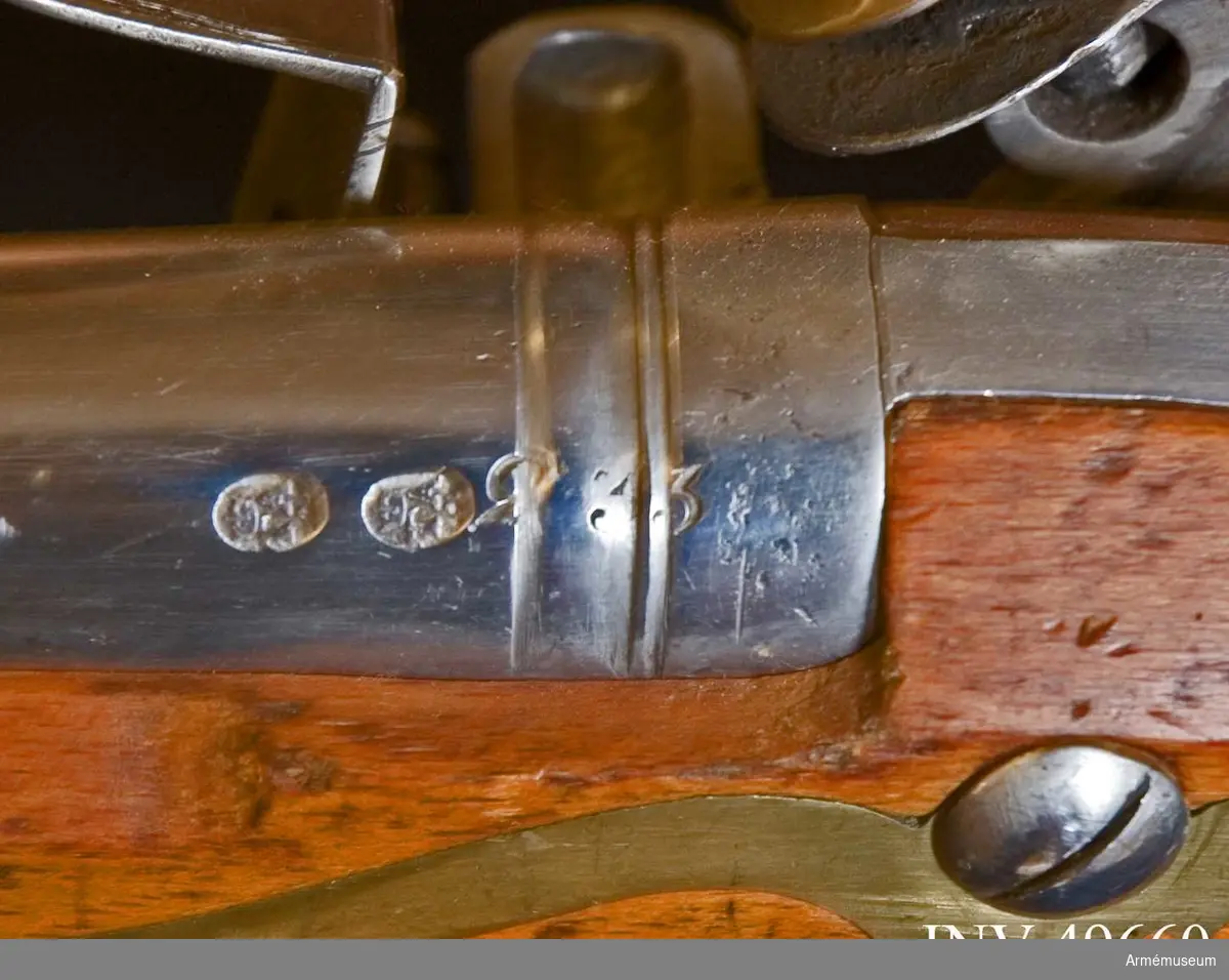 Grupp E XIV.
Loppets relativa lopp är 57,1 kal. Afrikanskt gevär med flintlås. Tjockare gods i pipan än på AM.049655-9. På låsblecket otydlig text "Annely". Utan reversal. På  pipans vänstra sida återfinns två stämplar med krönt TA.