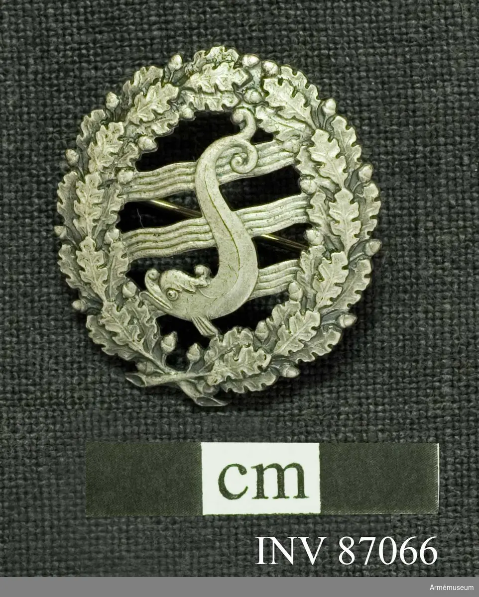 Grupp M.

Simförbundets magistermärke i silver.

Materialet är silver, vilket framgår av den på frånsidan befintliga kontrollstämpeln och arsbokstaven O 8.//Prn.