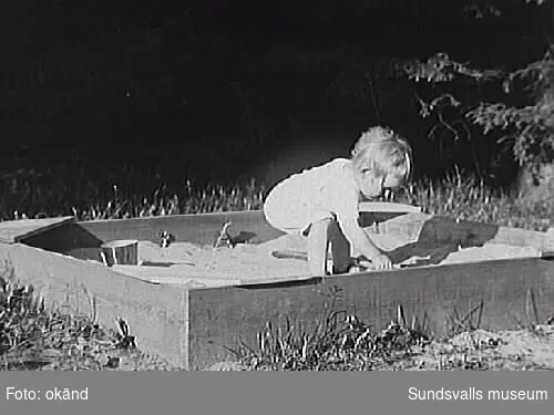 Barn leker i sandlåda. Barnet är förmodligen något av Lennart och Pussi Norströms barn. Barnet är barnbarnsbarn till Grosshandlare Christian Fredrik Ernestus Bünsow.