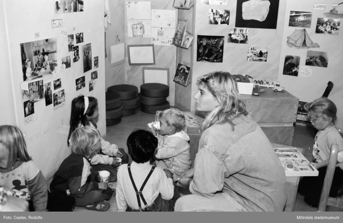 Några barn och en vuxen sitter på golvet i samband med en utställningsvernissage av och om Katrinebergs daghem på Mölndals museum 1993-09-10.