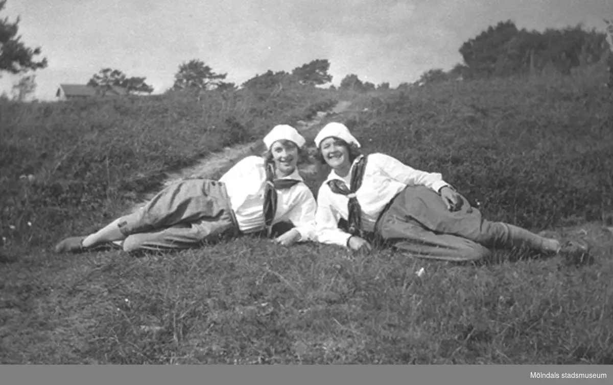 Karin Hasselberg (till höger) och en väninna. Båda ligger i gröngräset iförda fritidskläder, 1940-tal. Relaterat motiv: 1995_0686.