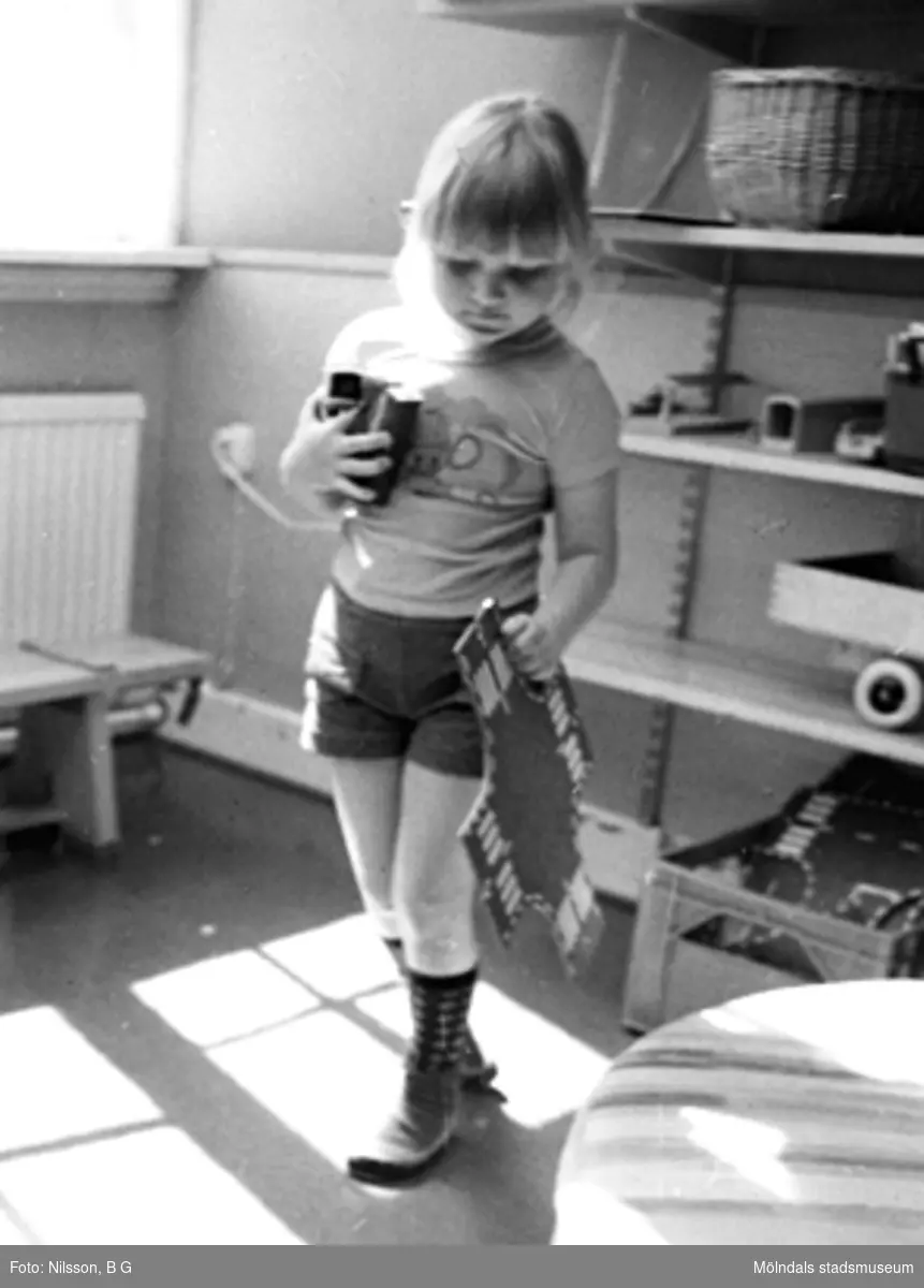 En flicka som håller leksaker i sina händer. Holtermanska daghemmet, okänt årtal.