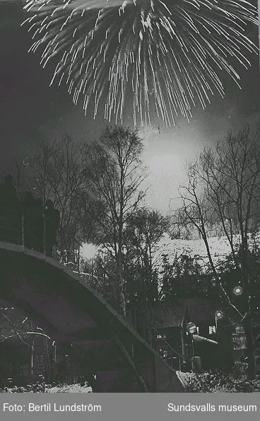 Fyrverkeri med anledning av kommunsammanslagningen, Stor-Sundsvalls tillkomst. Fotografiet är taget vid midnatt mellan 31 decembef 1964 och 1 januari 1965, med Puckelbron och Norrmalm i bakgrunden.
