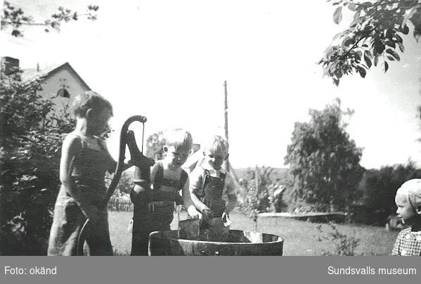 Anders, Lars och Håkan pumpar upp vatten för blomvattning, Sallyhills gård, 1946. Sallyhills gård var Maiken Bryners barndomshem.