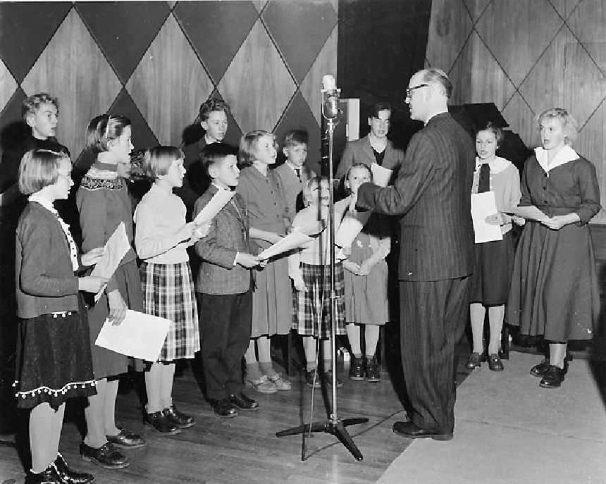 Skolklassen från Holmön sjunger sin egen sparvisa under ledning av
sin lärare komminister Sigfrid Landin.