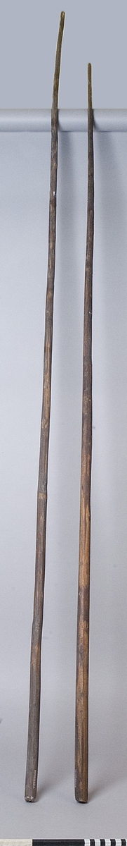 Brödstång, två stycken av trä, gjorda av två avbarkade unga träd och troligen betsade. Den långa är något böjd.