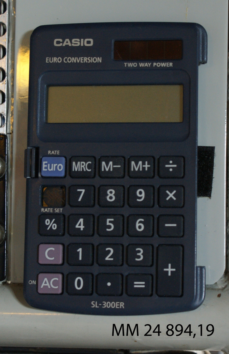 Miniräknare Casio. Rektangulär blå-grå apparat med knappar med vit text. Digital display. Märkt: "Casio Euro conversion SL - 300 ER".
