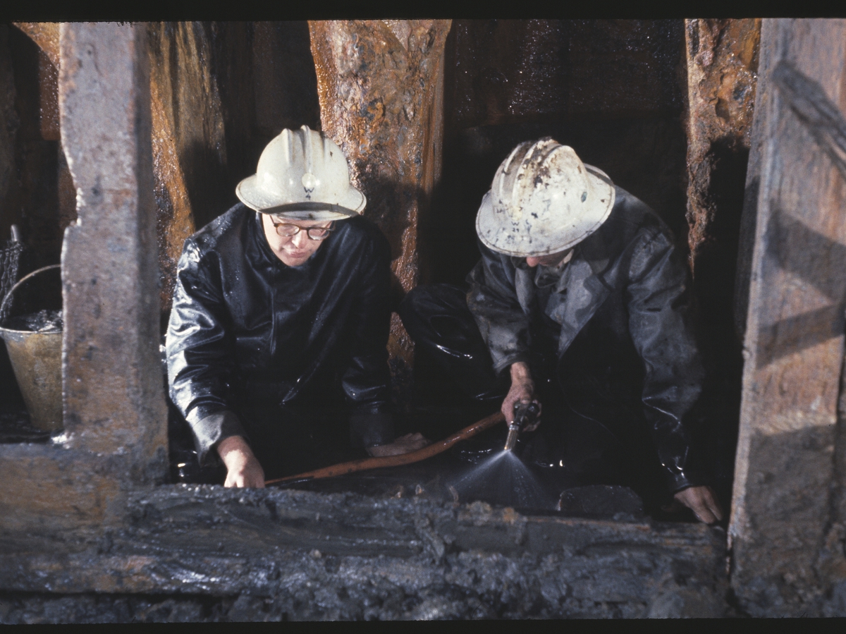 Arkeologerna Göran Bergengren (t.v.) och Jonas Ferenius (t.h.) rensar ett föremål från lera och slam med lätt vattenstråle, i Vasas hålskepp.