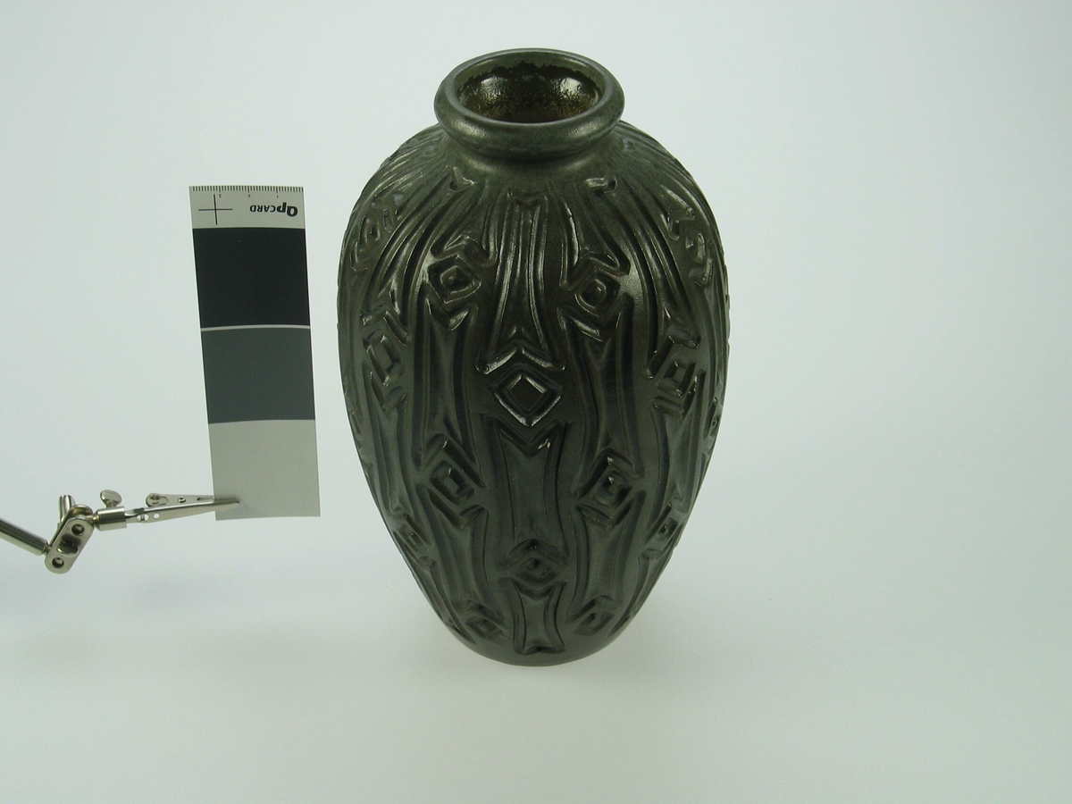 Rund vase som blir bredere mot midten. Vasen er dekorert med et mønster som består av streker og firkanter.
Åå undersiden av vasen finner man symbolet kk ( Kråkerøy keramikk) og tallet 547.