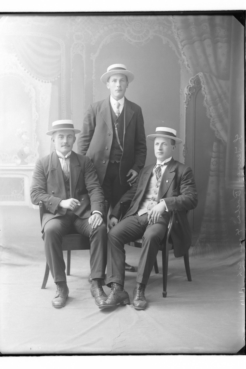 Studioportrett av tre menn med stråhatter.