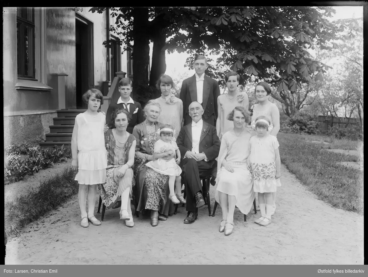 Familie fotografert ved inngangspartiet til hus. Sarpsborg-distriktet 1929. Ukjente personer.