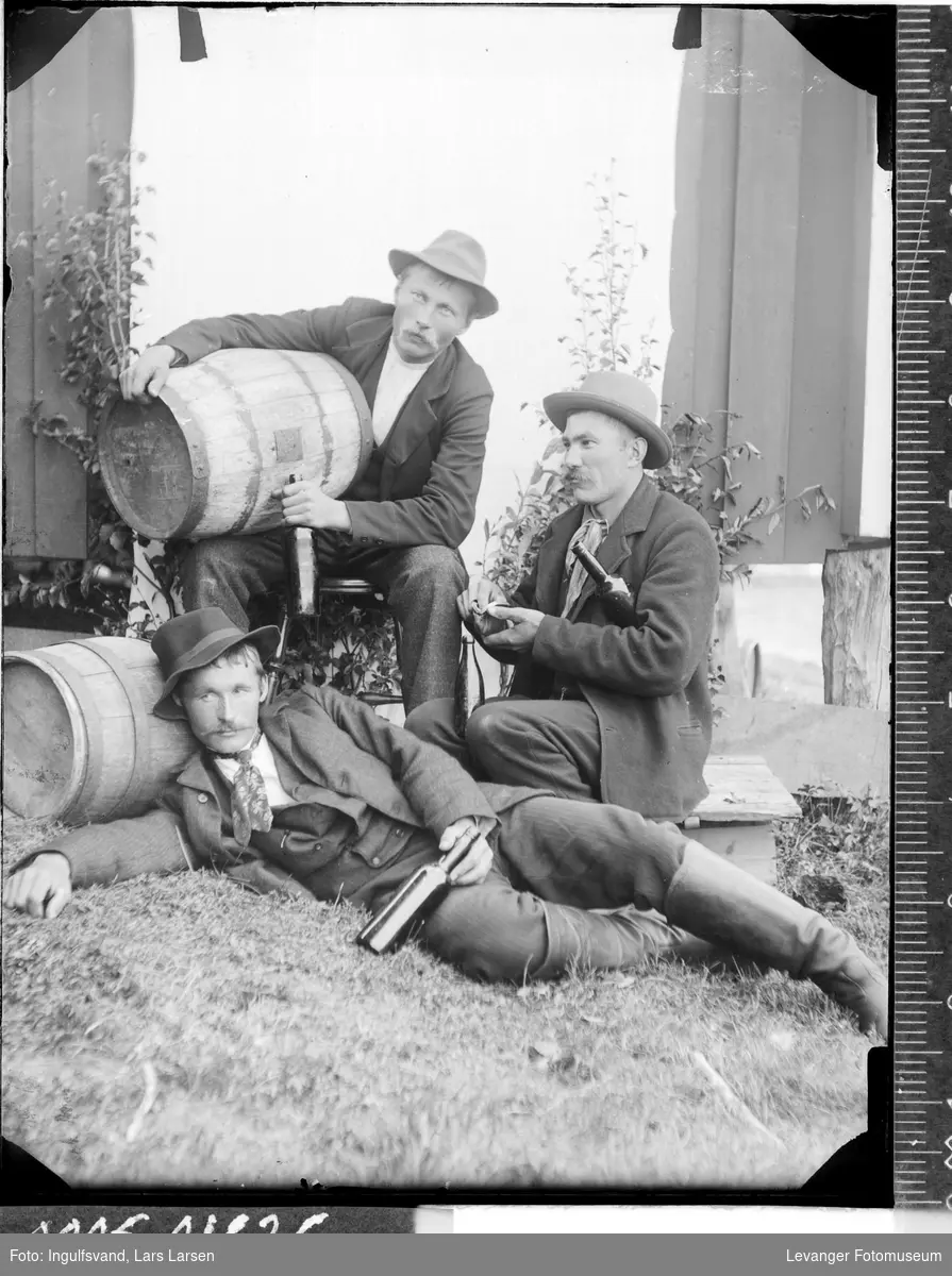 Gruppebilde av tre menn med vintønner og flasker.
