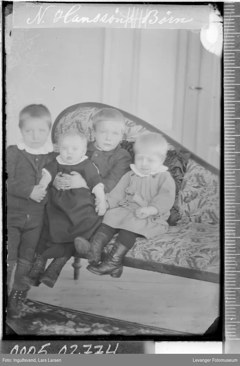 Gruppebilde av fire barn på en sofa.