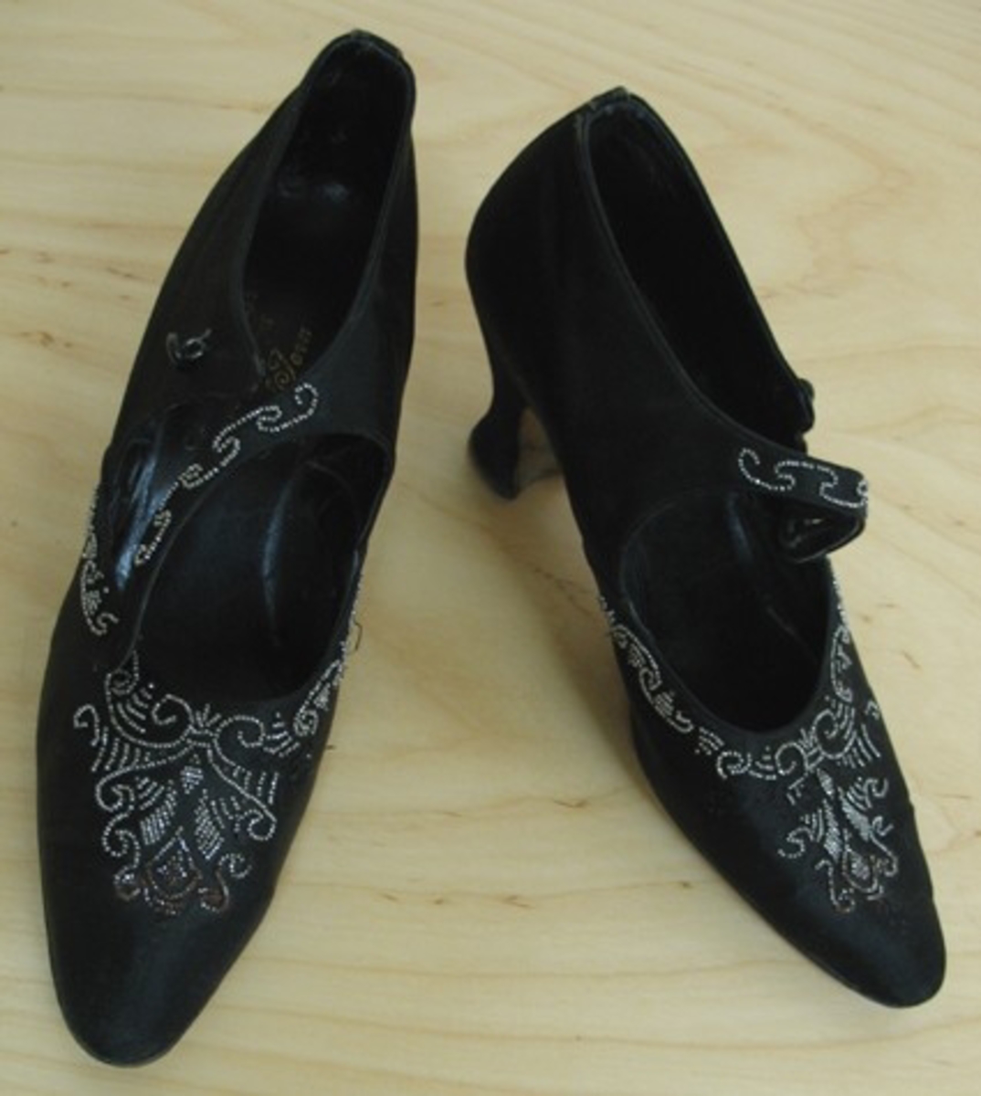 21 205:a Höger sko.
:b Vänster sko.

Skor i läder klädda med svart sammet. Skorna öppnar sig 8 cm, från tån och knäpps över foten med ett enkelt ca 1 cm, brett band som knäpps med en rundad lackad knapp.

Skorna har rika pärlbroderier i silverfärgade pärlor på tån, längs sidorna och på bandet.

Skorna är invändigt märkta ''Chaussures de Luxe Importées par Carl Jern Stockholm''. Undertill är de märkta ''E Import, 730, 36, 5''. Enligt uppgift är de inköpta på 1930-talet.

Givaren var bosatt i Skara 1938-1958.