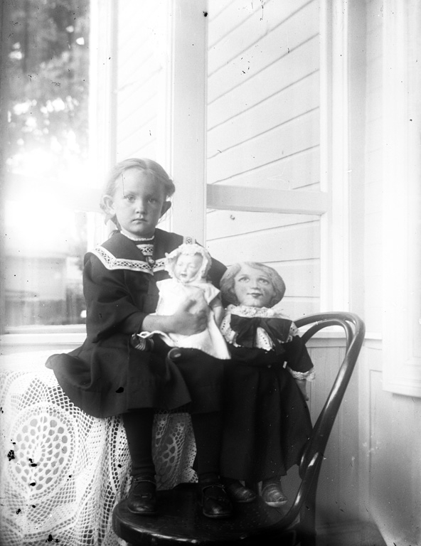 Text till bilden:"Flicka med docka, på stol".