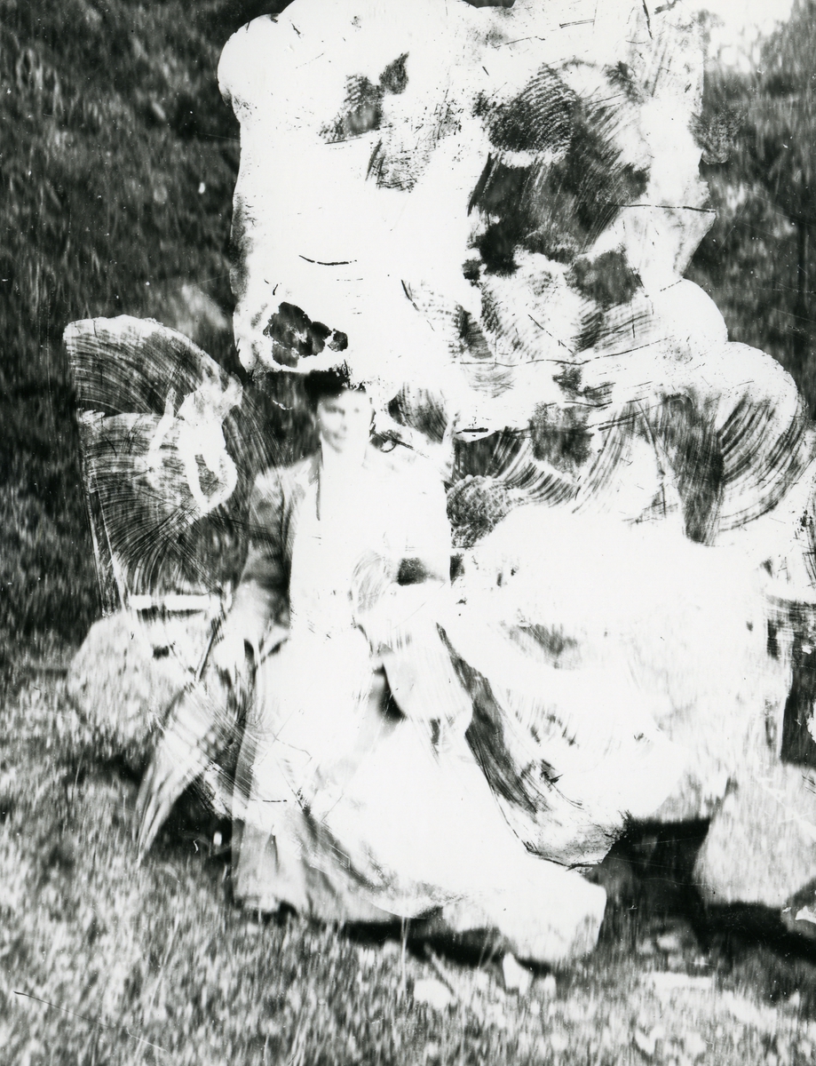 Kvinne sittende på stein i skog