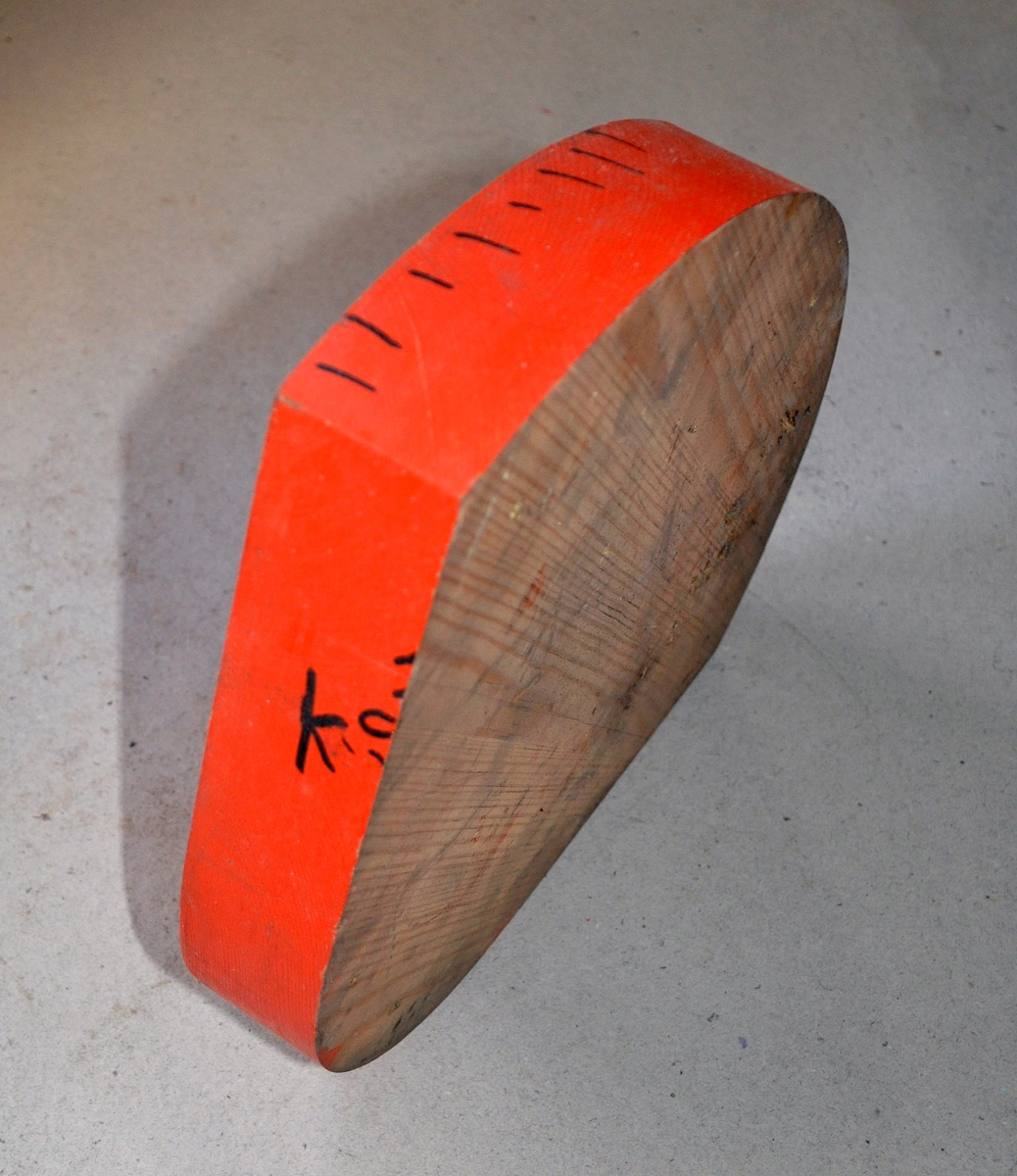 Støpemodell av tre med skruehull. Skive til å bygge opp porthengslene med. Oransj farge og to sorte prikker på.