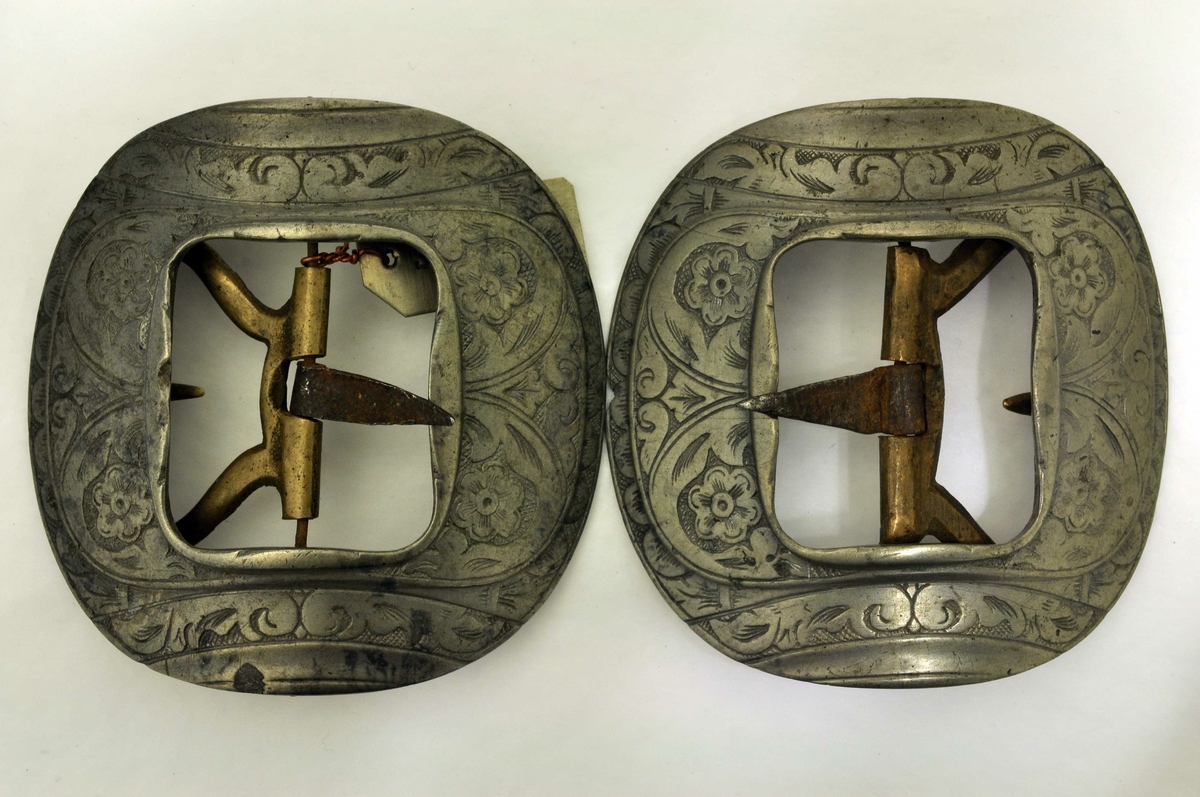 Fra protokoll: 1 par skospæder i renæssance. Av jern med spjotr-belæg og bronsenaale. Sterkt kvælvede, med hugne rankeornamenter.