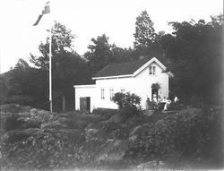 Lite hus mellom knauser og skog, gruppe rundt bord utenfor