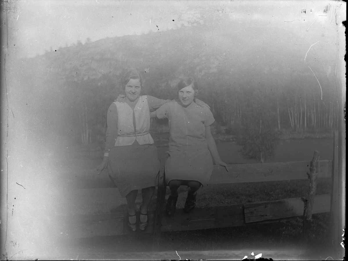 Elsa Rosengren och en släkting sittande på en gärdsgård.