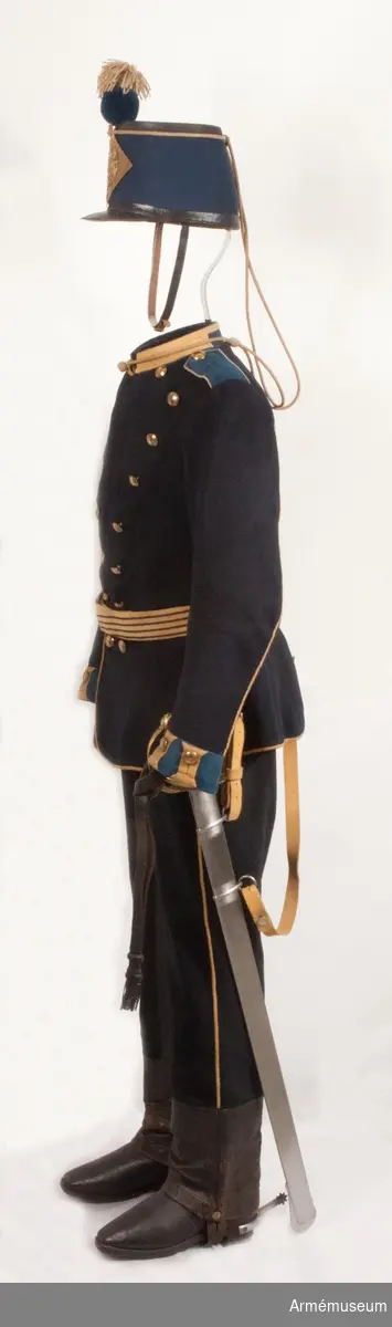 Grupp C I.
Vapenrock av mörkblått kläde med ljustblå detaljer samt gult ullgarnsband för distinktionskorpral.
