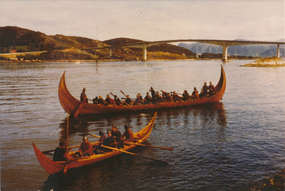 Store og lille Kvalsundskip foran Herøybrua, med mannskap i vikingtidsmundur. Skipa er rekonstruksjoner fra ca. år 700 e. Kr. og er de eldste i Norge.