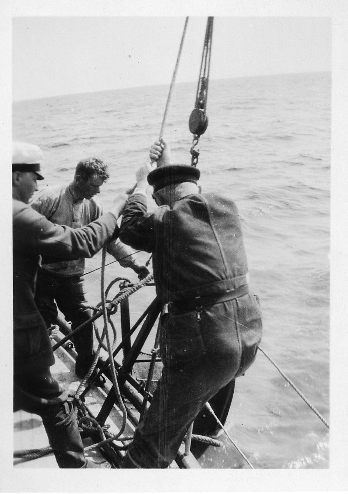 'Från ''Akka'' expedition sommaren 1929: ::  :: Leonard Axel Jägerskiöld (ryggen mot kameran) och 2 män vid relingen arbetar med skrapan. ::  :: Ingår i serie med fotonr. 1862-1864.'