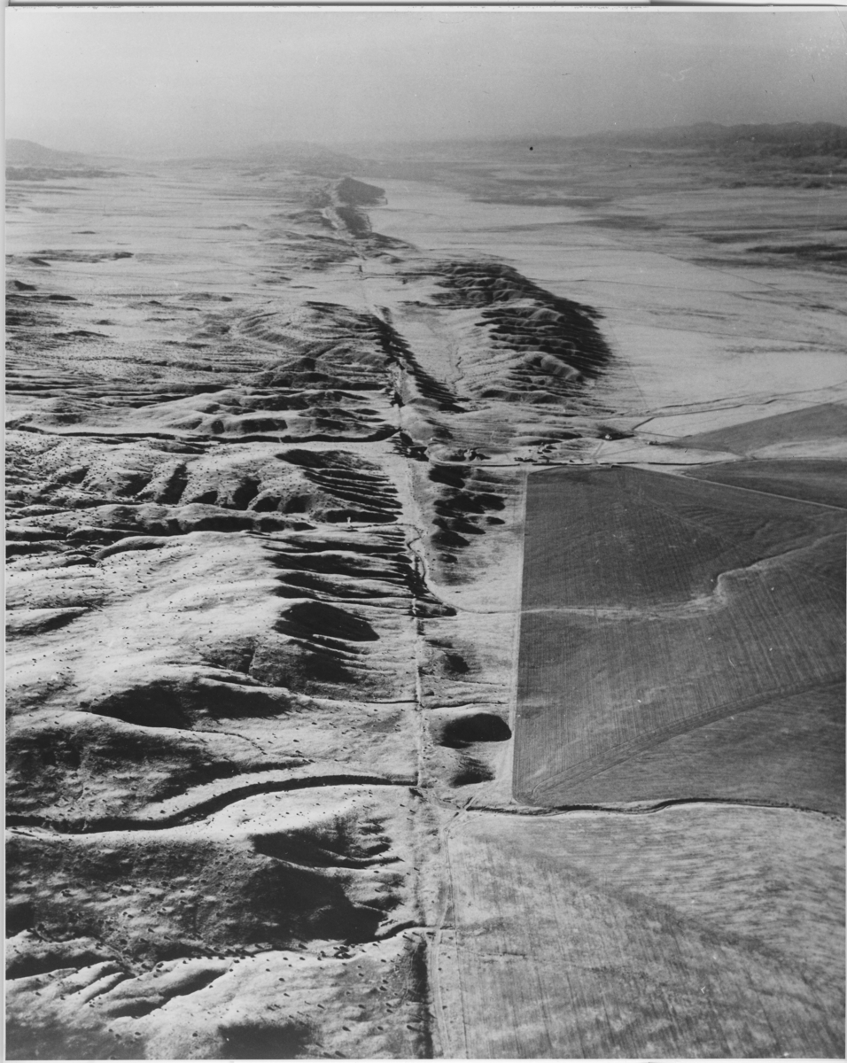'Flygbild över San Andreasförkastningen. :: Enligt text på baksidan '' View looking south along San Andreas fault., Elkhorn Scarp. Carrizo Plains is on the right - Elkhorn is on the left.'' :: Ingår i serie med fotonr. 5664:1-3.'