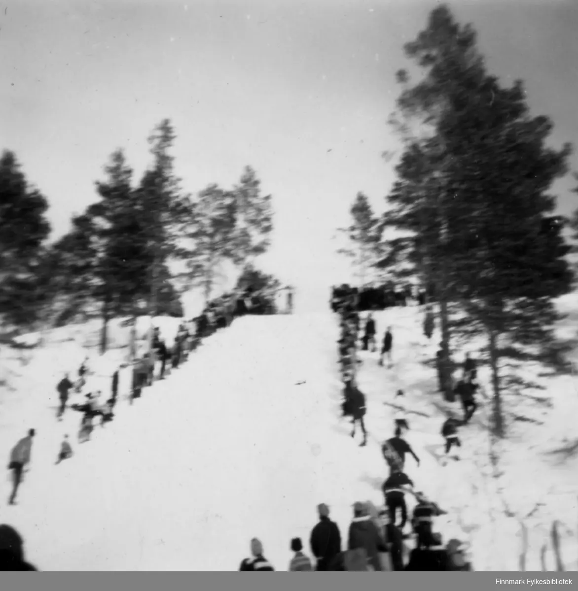 Hopprenn i Karasjok. En del tilskuere står i bakken og nede på sletta.