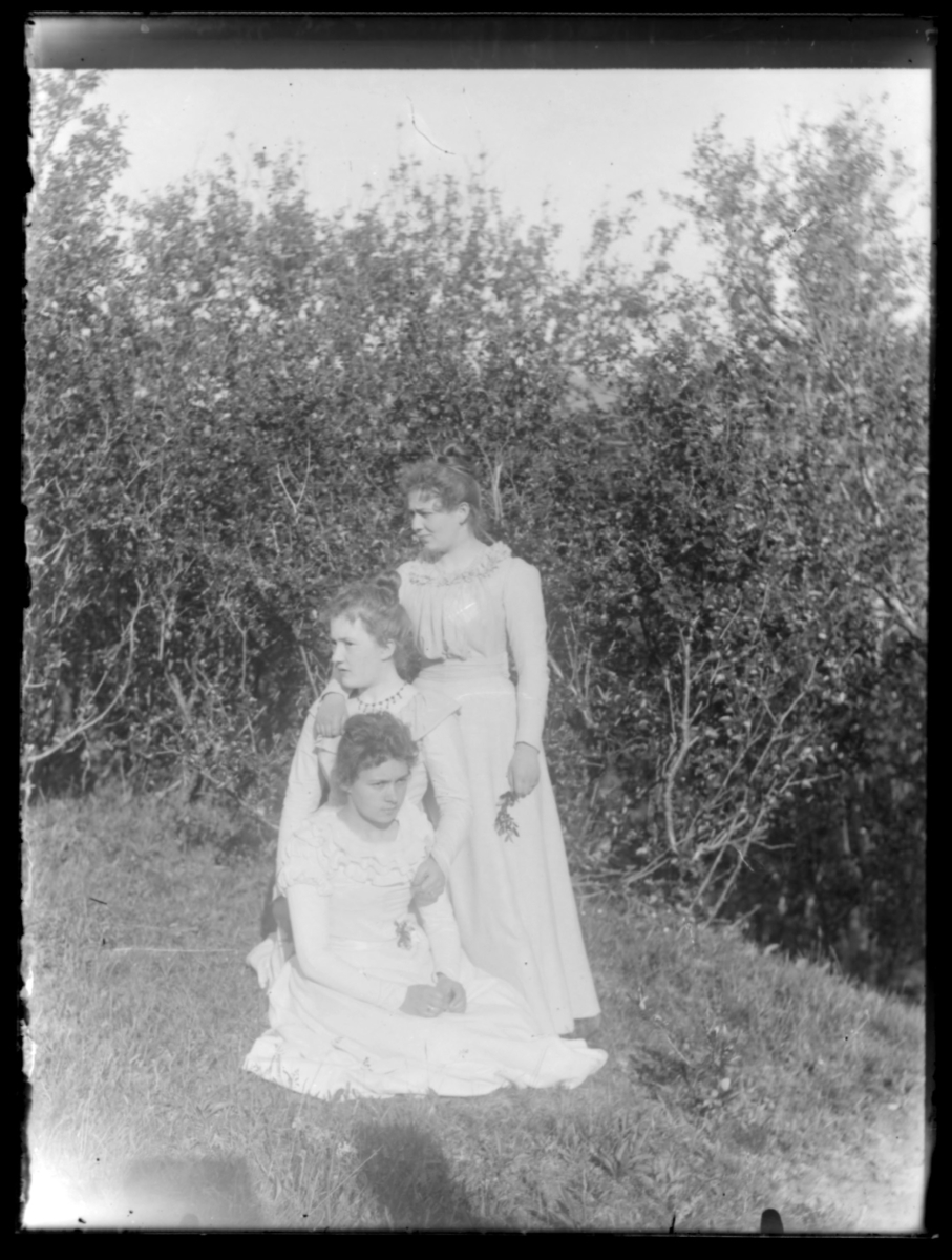 Tre kvinner i hvite sommerkjoler fotografert ute