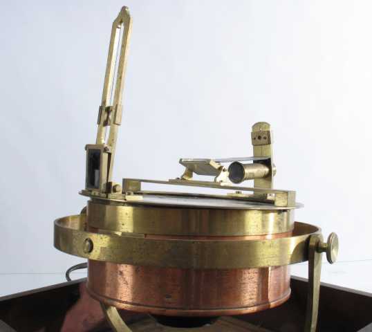 Kasse av mørk eik, i den er montert et instrument av jern og messing. 