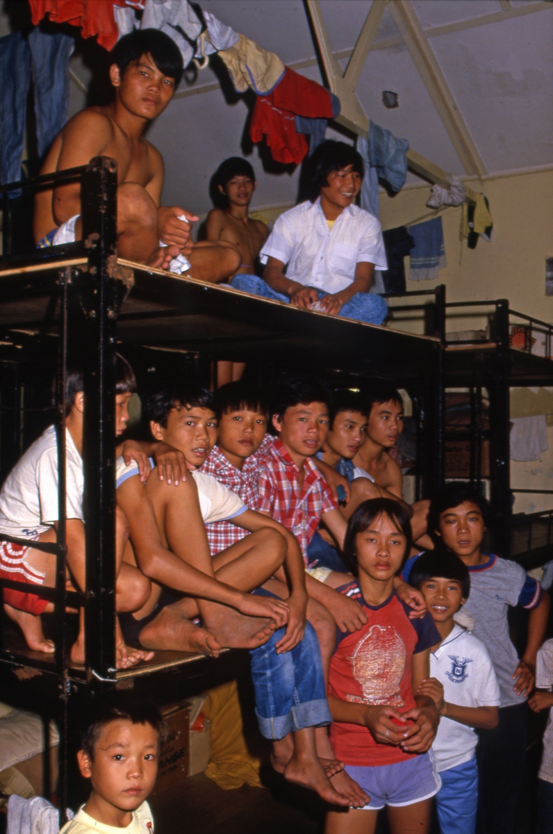 Barn poserer foran tre-etasjes køyesenger i Tuen Mun flyktningeleir i Hong Kong.