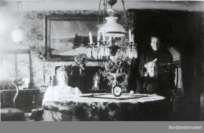 Interiørbilde fra Kjerringøy. Fra venstre Sofie Amundsen, Anna Elisabeth Kristiansen (stående) og Elise Gotaas, deres mor. 