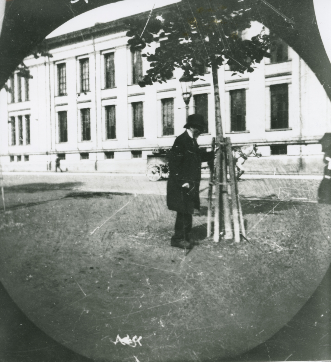 Ivar Aasen ved universitetet på Karl Johanes gate, Kristiania, om lag 1892. Aasen stør seg til eit tre, og ser gammal og trøytt ut.
