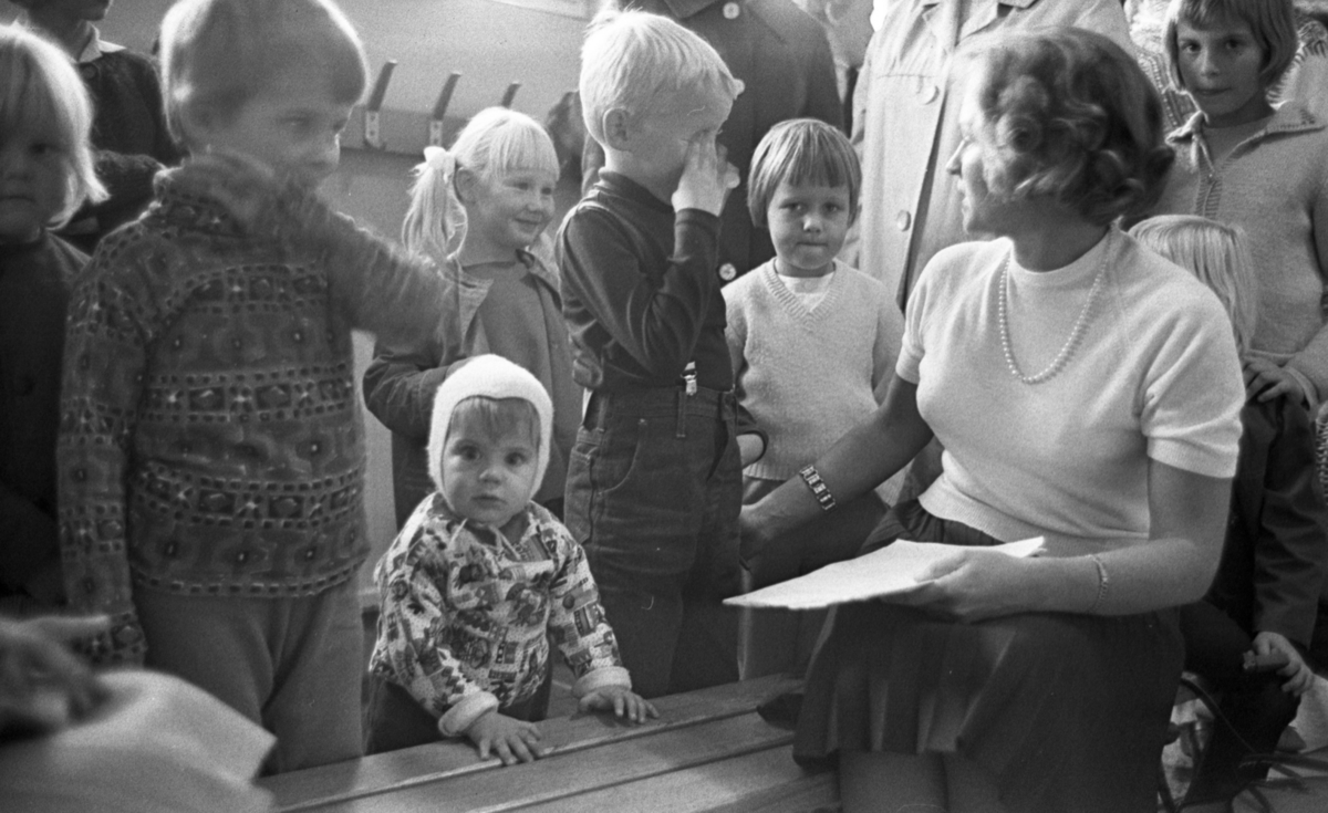 Inskrivning barngymnastik 15 september 1965

Barnen som ska skrivas in samlas runt lärarinnan,  Inga Pettersson, tillsammans med några föräldrar. Flera av barnen skrattar. Några ser in i kameran, bland dem en 1-2 åring.